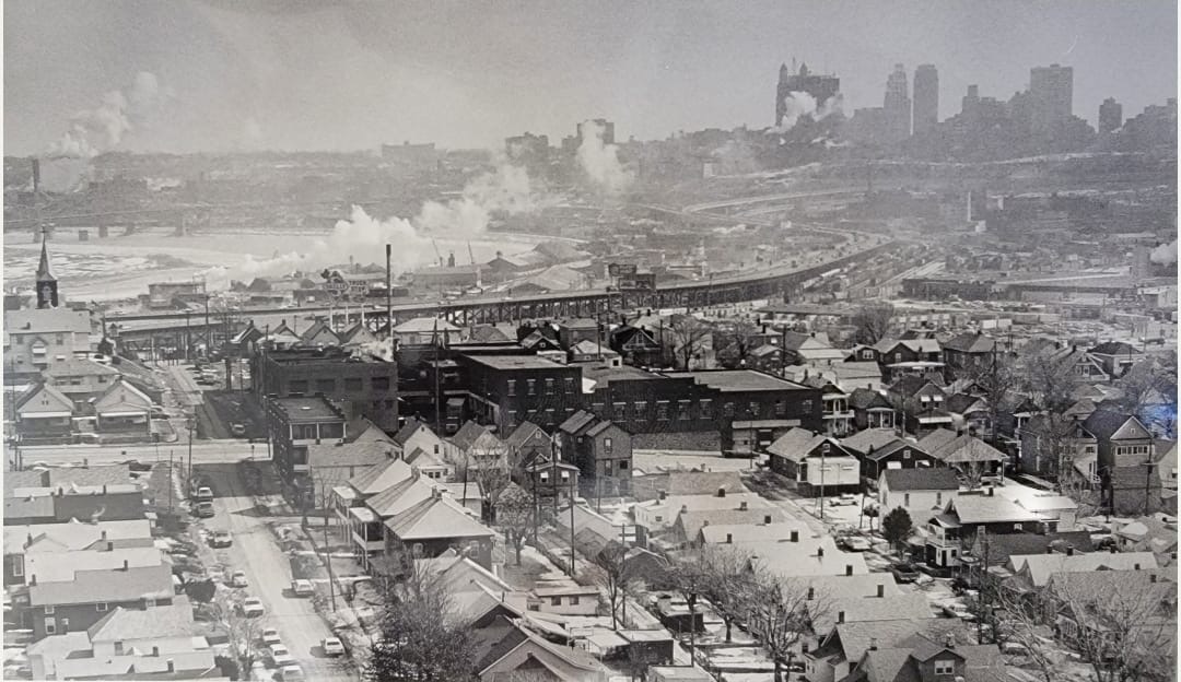 A vintage winter aerial of the Strawberry Hill neighborhood with the historic warehouse in the foreground and the downtown Kansas City skyline beyond